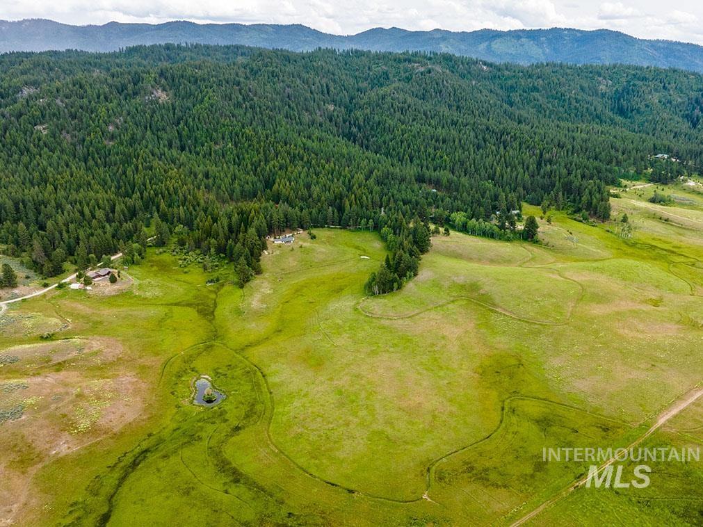 10885 Callender Road Cascade, ID 83611 - Photo 4 of 31 Expansive land parcel featuring verdant fields, a natural pond, and a winding stream