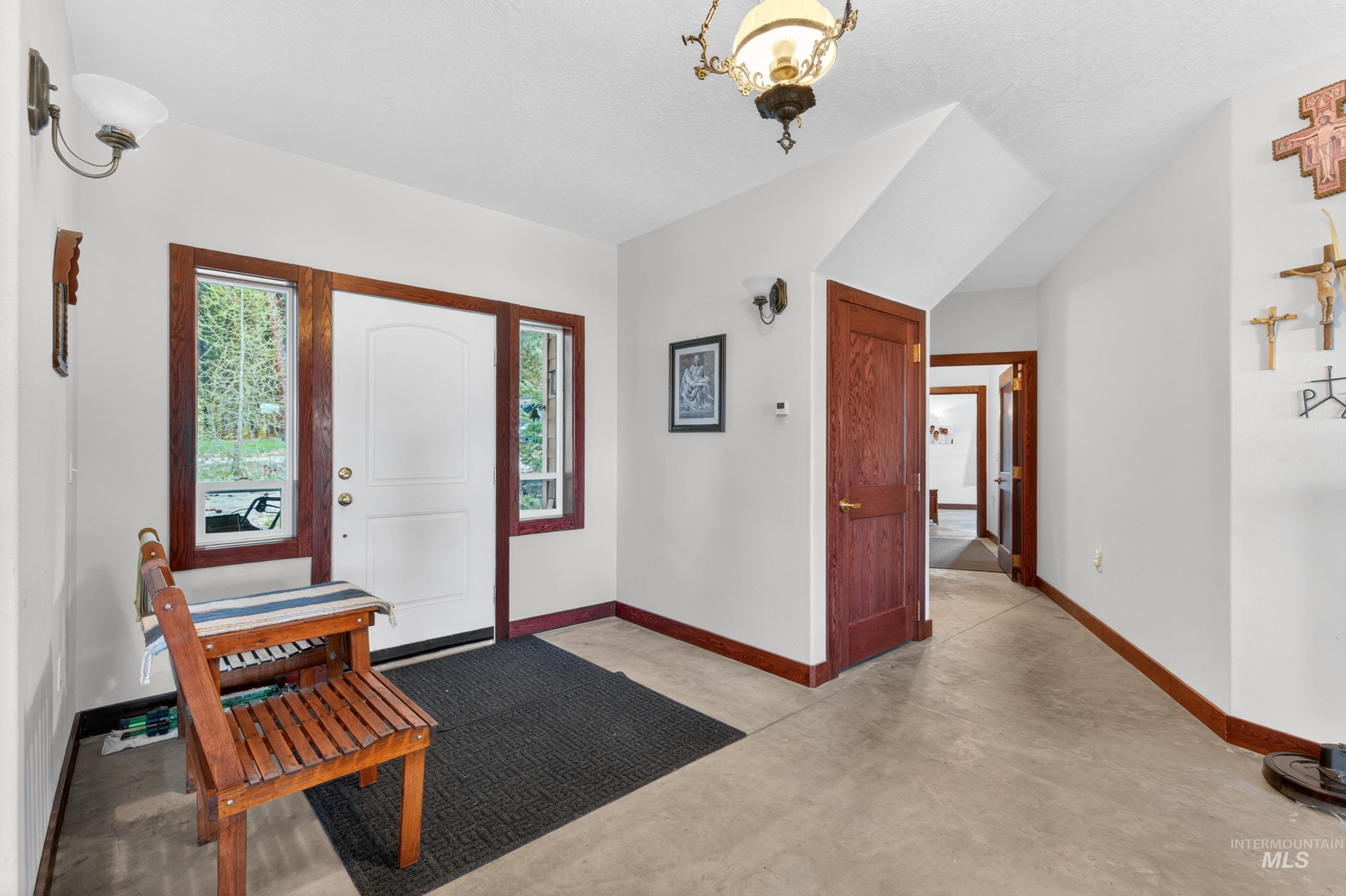10885 Callender Road Cascade, ID 83611 - Photo 9 of 31 Entryway featuring a white paneled door with sidelight windows, dark wood trim, concrete flooring, and a decorative ceiling light fixture