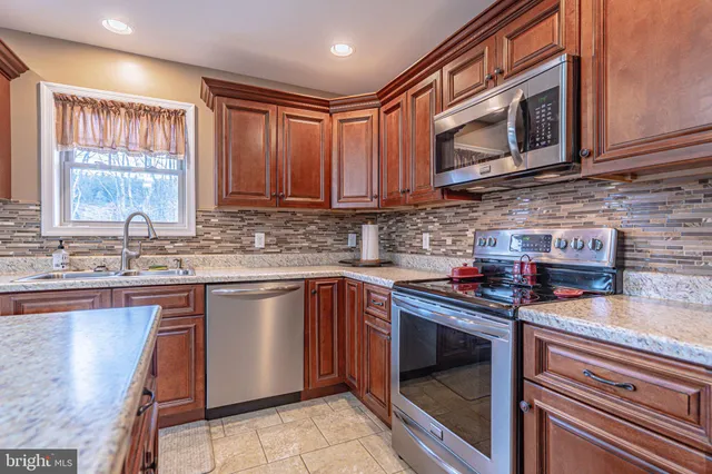 a kitchen with stainless steel appliances granite countertop a stove top oven a sink dishwasher a dining table and chairs with wooden floor