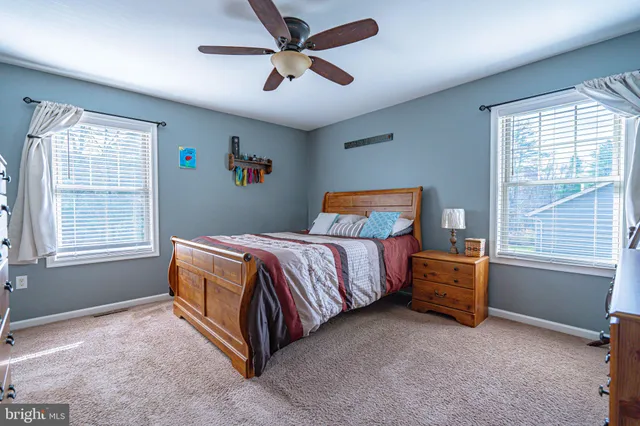 a bedroom with a bed a dresser and a chandelier