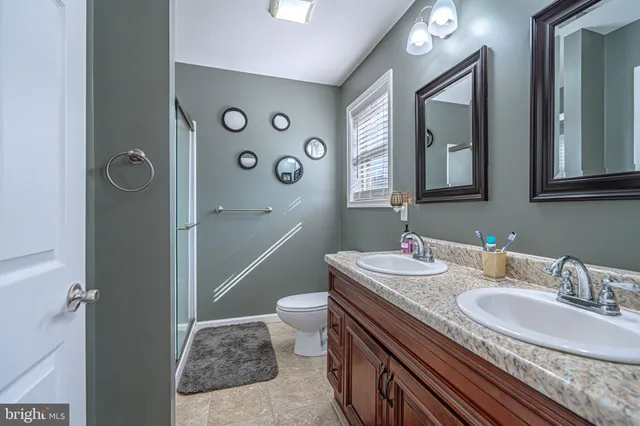 a bathroom with a granite countertop shower a sink and a mirror