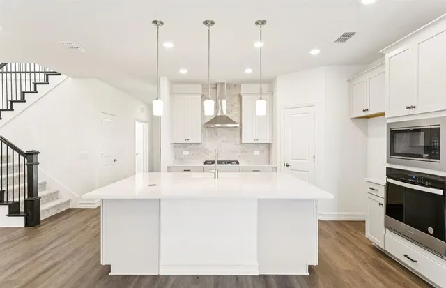 a large kitchen with kitchen island a stove a sink a center island and wooden floor