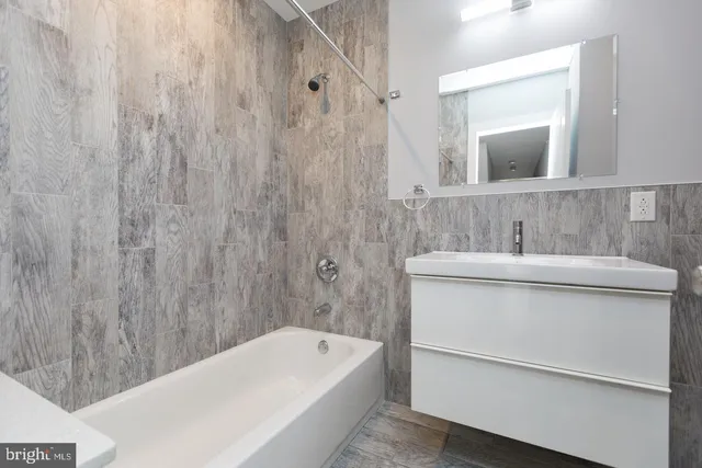 a bathroom with a sink a bathtub a mirror and vanity