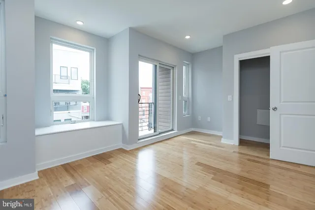 an empty room with wooden floor and windows