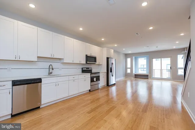 a open kitchen with stainless steel appliances granite countertop a stove top oven a sink dishwasher and a oven with wooden floor