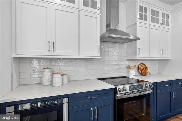 a kitchen with stainless steel appliances granite countertop a stove a sink and white cabinets