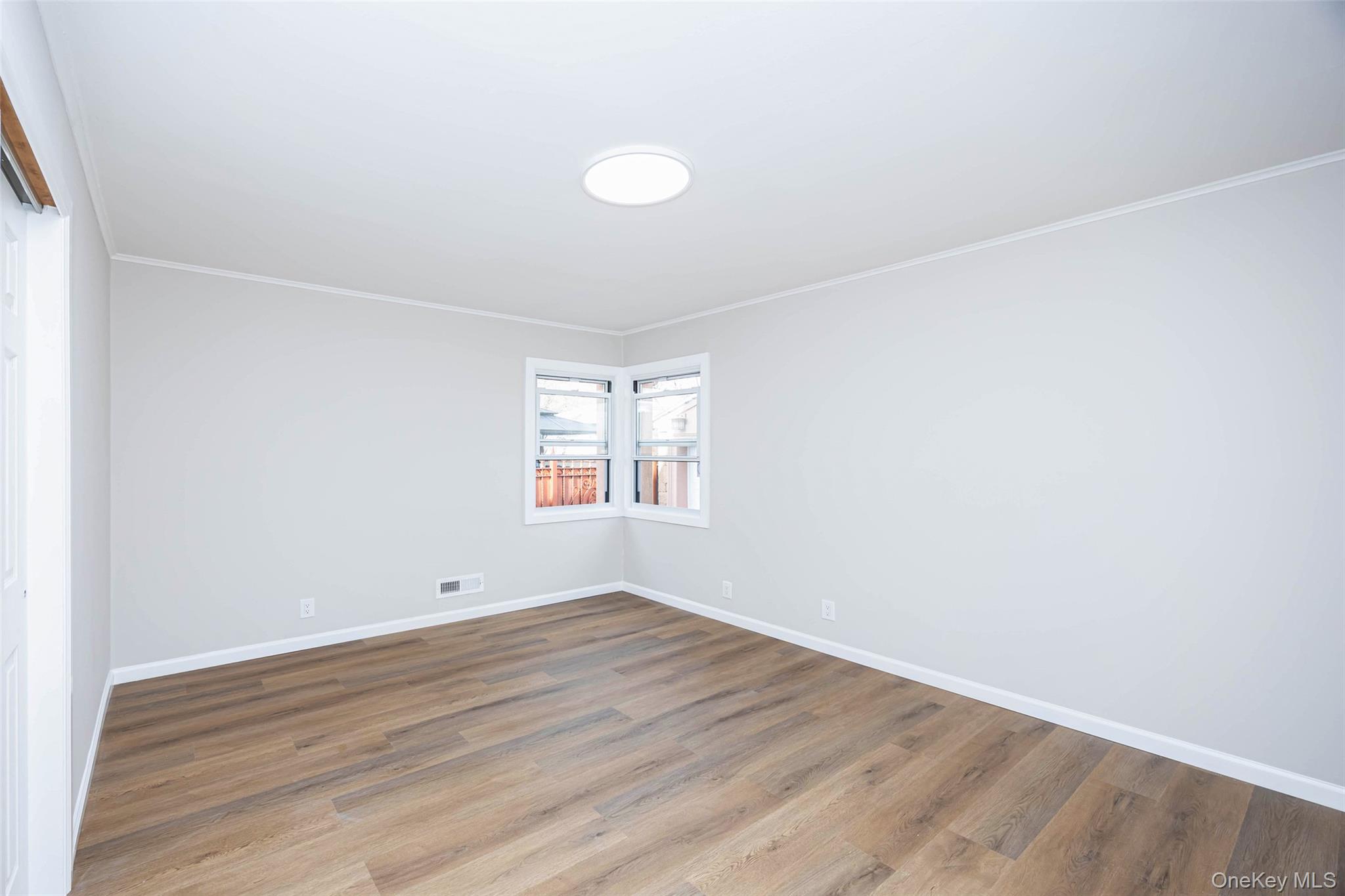 157-19 16th Road Queens, NY 11357 - Photo 15 of 33 an empty room with wooden floor and windows