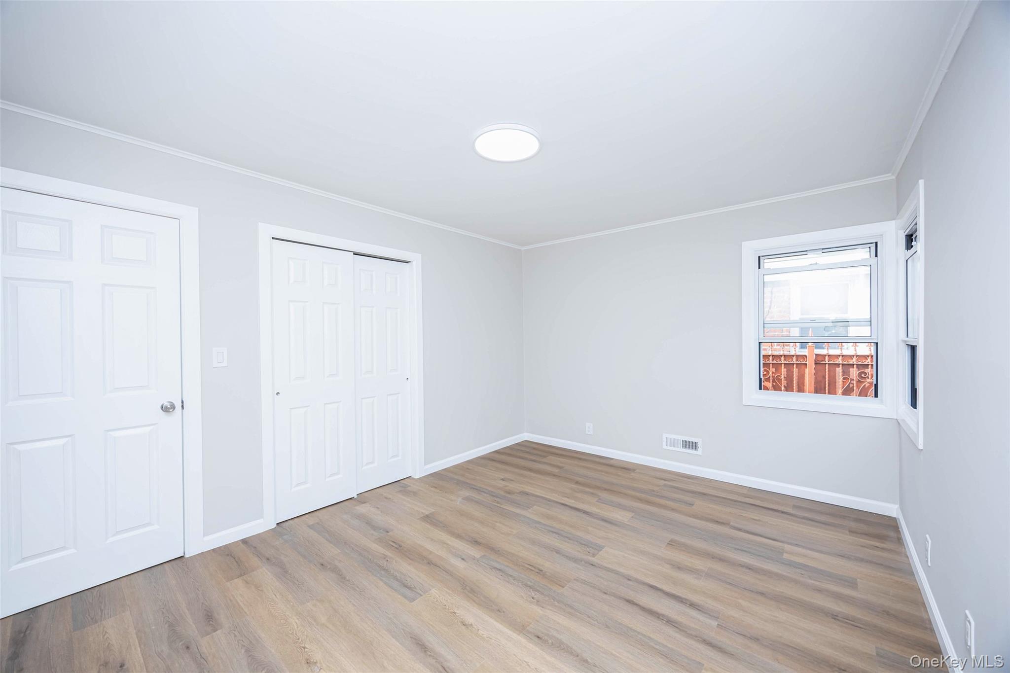 157-19 16th Road Queens, NY 11357 - Photo 16 of 33 an empty room with wooden floor and windows