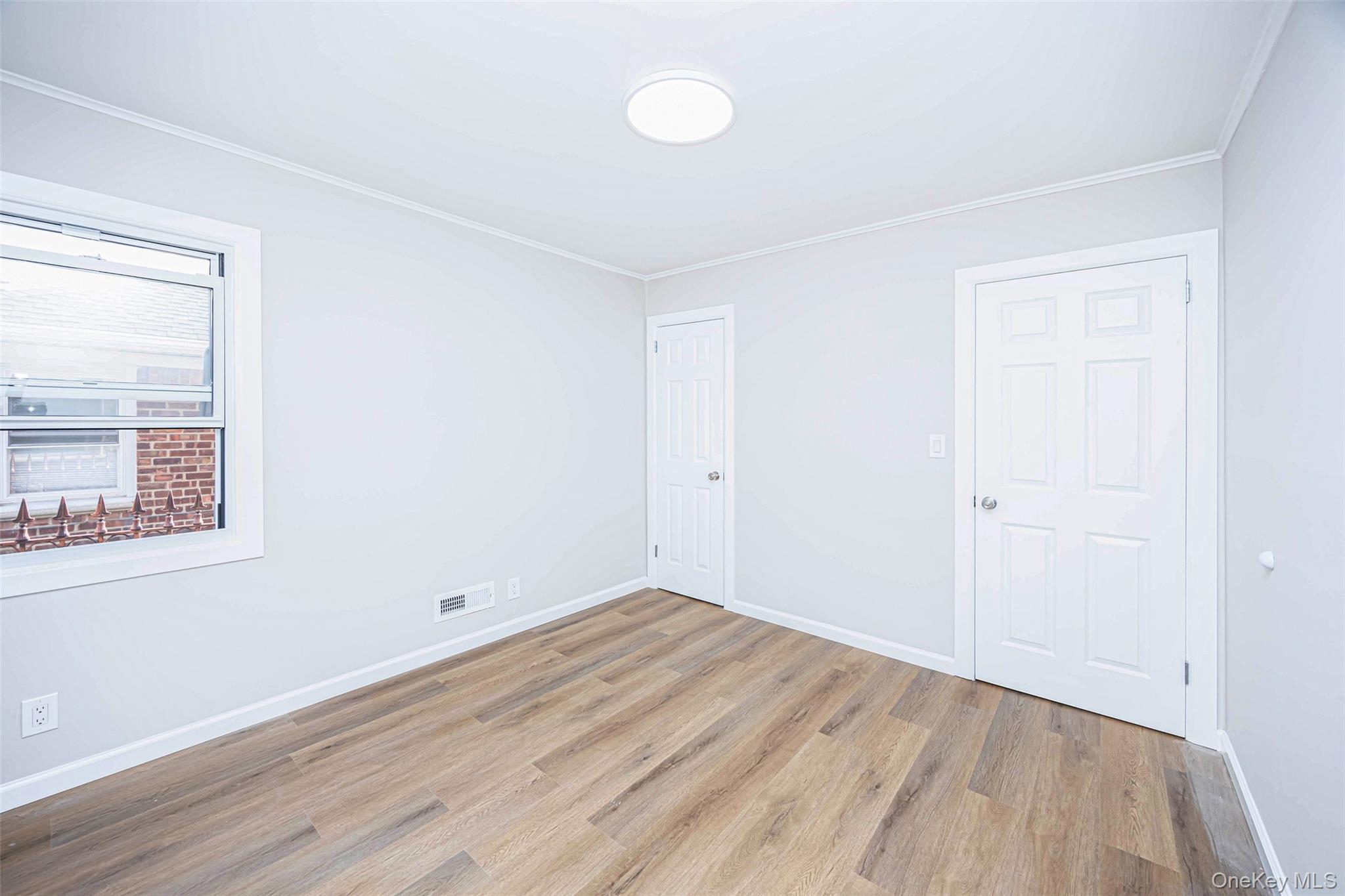 157-19 16th Road Queens, NY 11357 - Photo 18 of 33 an empty room with wooden floor and windows