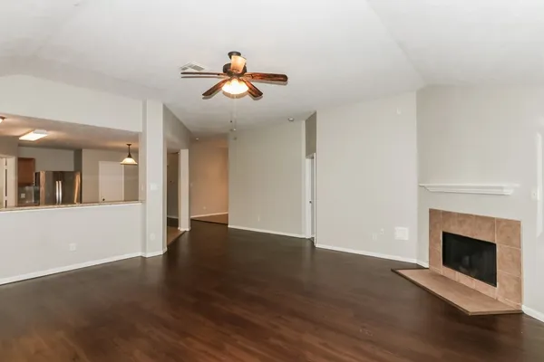 a view of an empty room with wooden floor and a fireplace