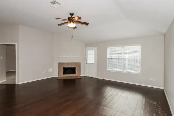 an empty room with windows fireplace and wooden floor