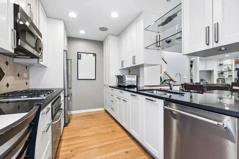 a kitchen with stainless steel appliances granite countertop a sink a stove and a refrigerator