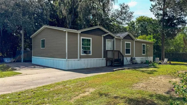 a view of a house with a yard and large tree