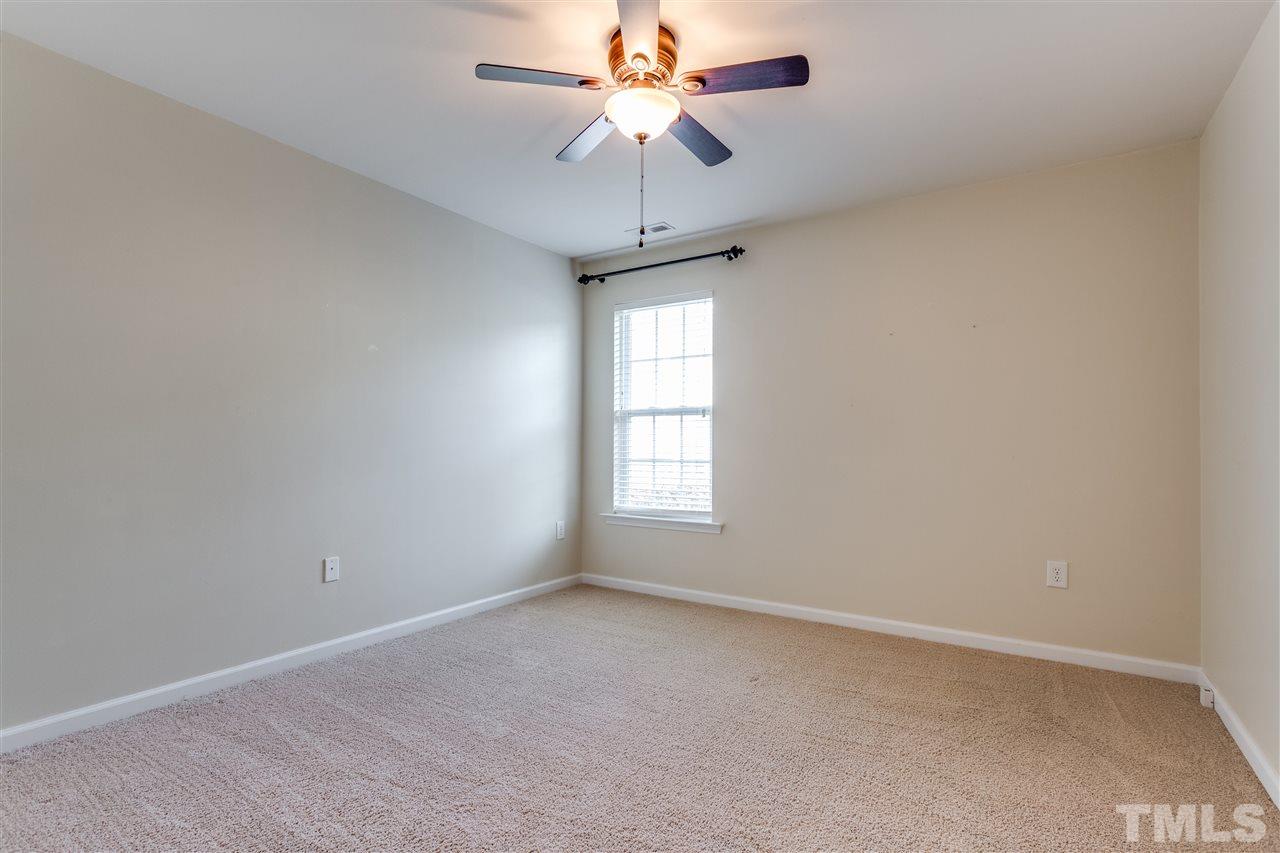 8702 Braxwood Place Raleigh, NC 27617 - Photo 21 of 24 an empty room with a chandelier fan and windows
