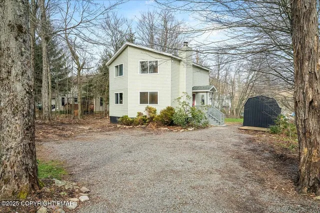 a view of a white house with a yard and large tree