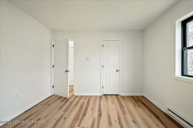a view of an empty room with closet and a window