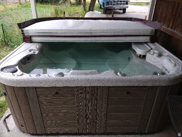 157 West 500 South Logan, UT 84321 - Photo 11 of 38 Outdoor spa featuring a textured acrylic shell, wood-look paneling, and a partially open cover