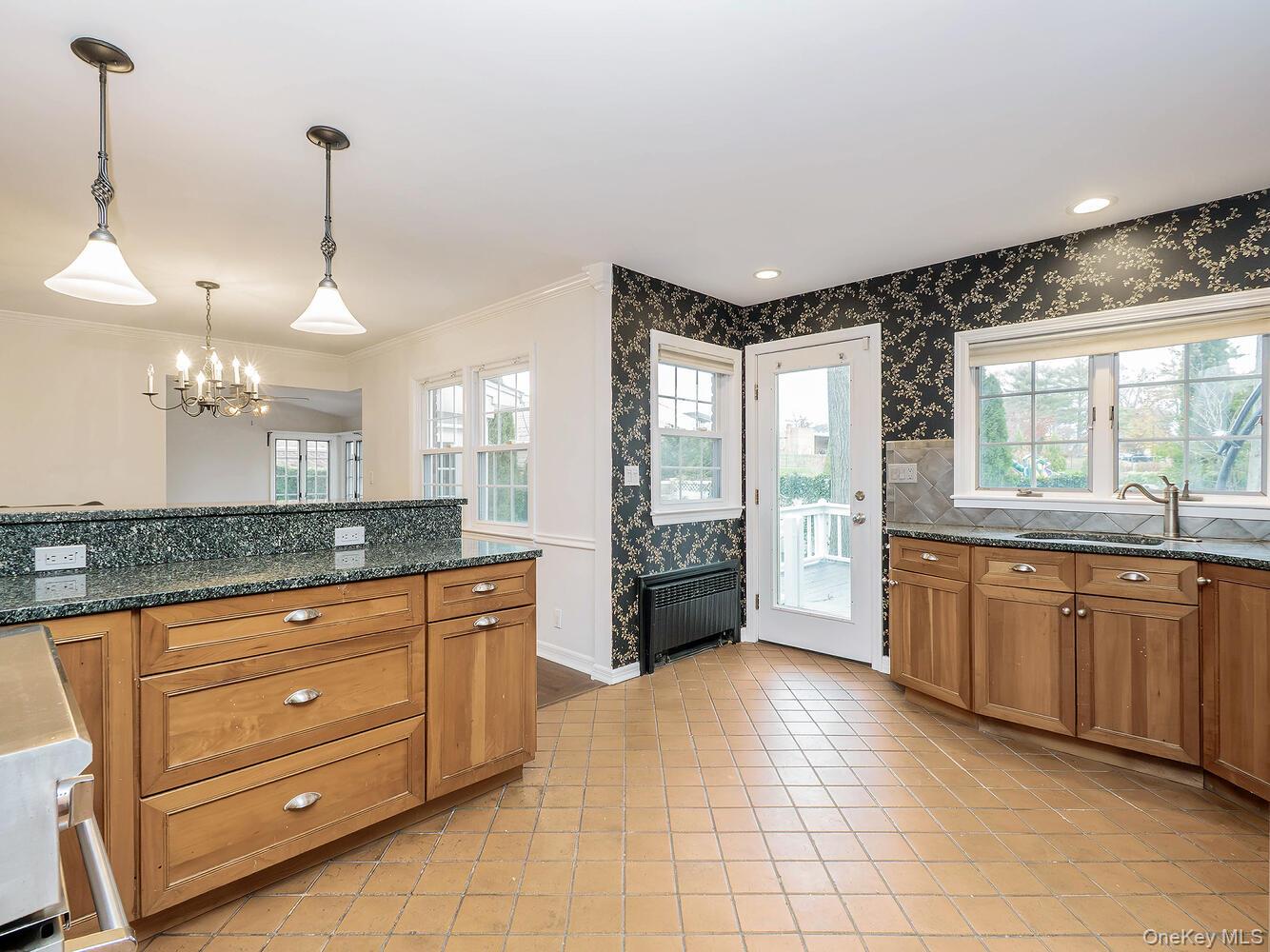 41 South 4th Street Locust Valley, NY 11560 - Photo 13 of 39 Kitchen with brown cabinetry, wallpapered walls, dark stone countertops, radiator, and hanging light fixtures
