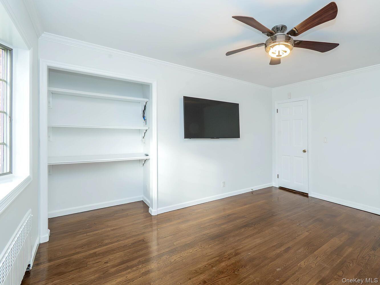 41 South 4th Street Locust Valley, NY 11560 - Photo 14 of 39 Unfurnished bedroom featuring ornamental molding, radiator, dark wood-style flooring, a ceiling fan, and a closet