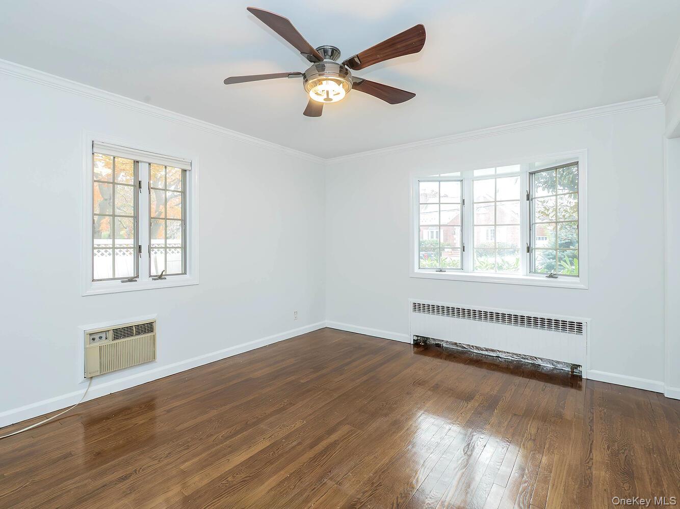 41 South 4th Street Locust Valley, NY 11560 - Photo 16 of 39 Unfurnished room featuring crown molding, radiator, dark wood-type flooring, ceiling fan, and a wall unit AC