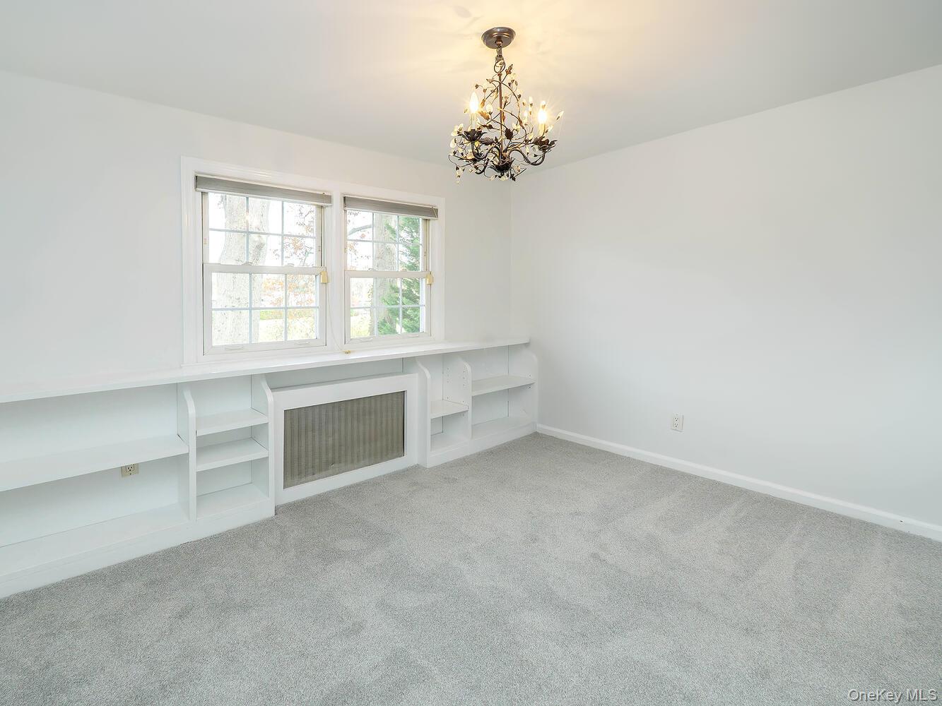 41 South 4th Street Locust Valley, NY 11560 - Photo 19 of 39 Unfurnished living room featuring radiator heating unit, light carpet, and a chandelier