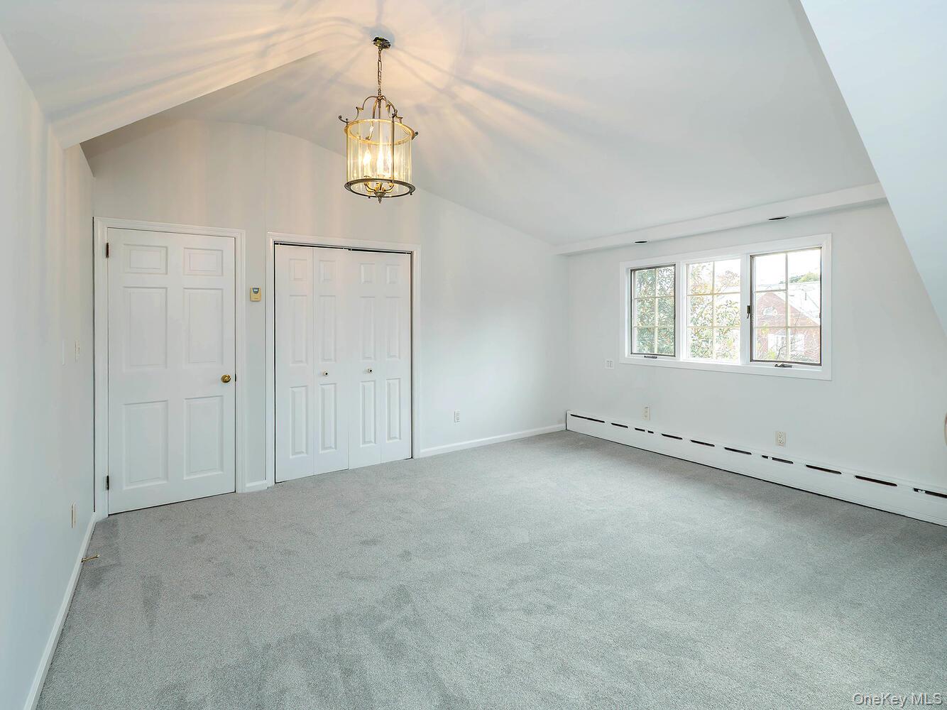 41 South 4th Street Locust Valley, NY 11560 - Photo 20 of 39 Unfurnished bedroom featuring vaulted ceiling, light colored carpet, a chandelier, and a closet