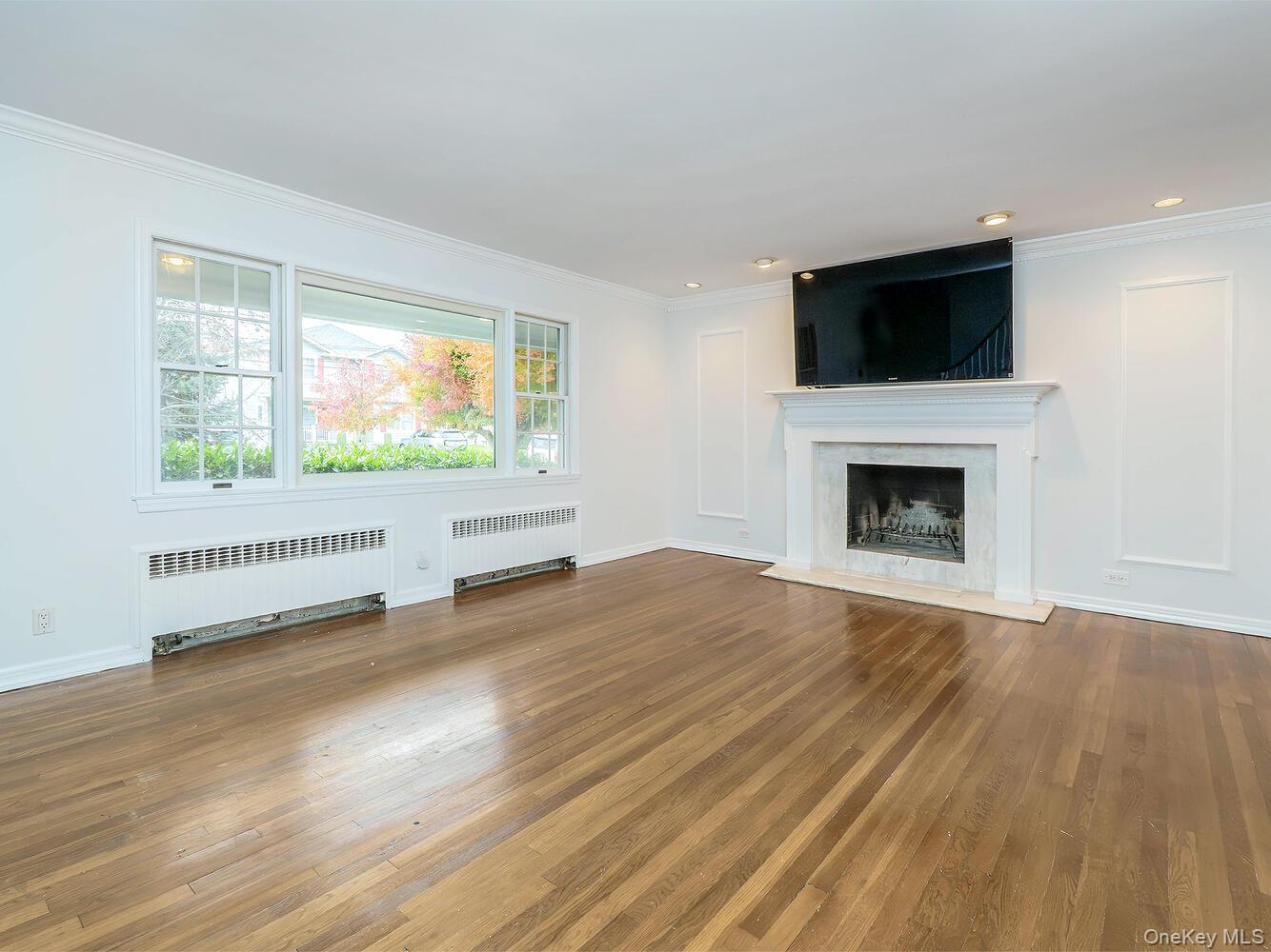 41 South 4th Street Locust Valley, NY 11560 - Photo 2 of 39 Unfurnished living room featuring radiator, ornamental molding, hardwood / wood-style floors, a high end fireplace, and recessed lighting