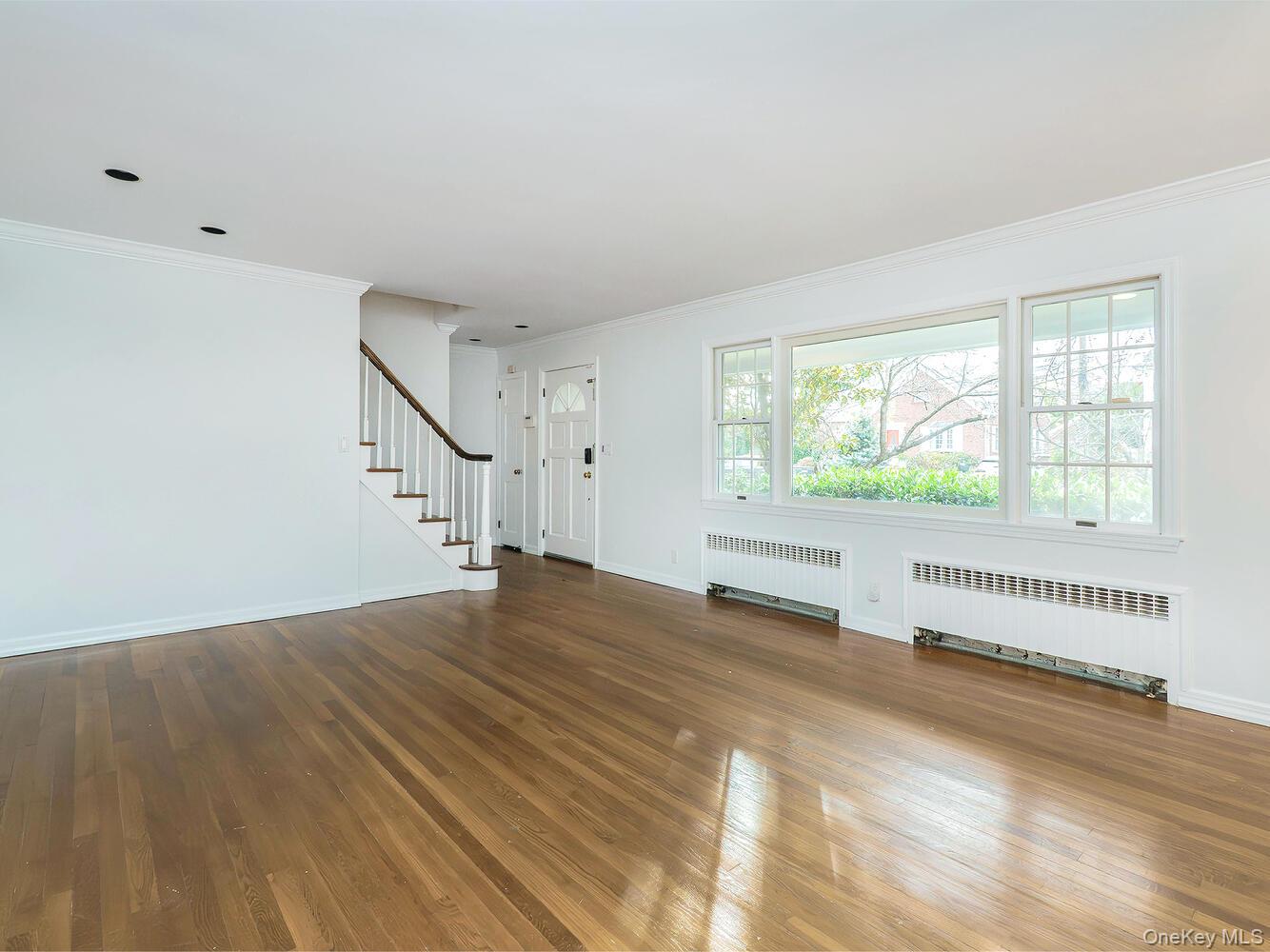41 South 4th Street Locust Valley, NY 11560 - Photo 3 of 39 Unfurnished living room with crown molding, stairway, radiator, and dark wood-type flooring