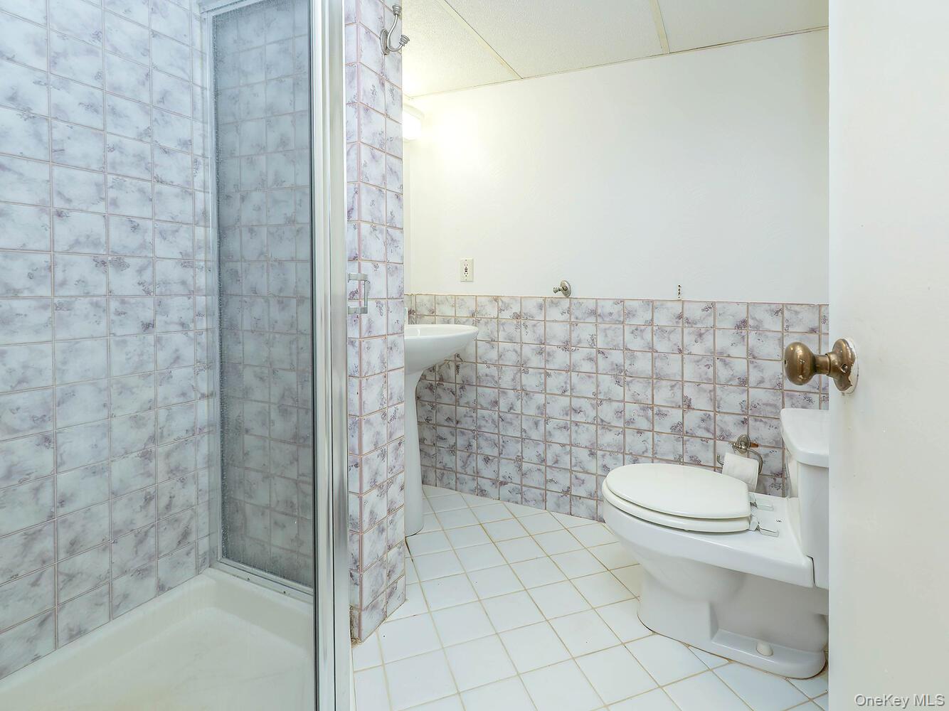 41 South 4th Street Locust Valley, NY 11560 - Photo 32 of 39 Full bathroom with tile walls, light tile patterned floors, wainscoting, and a stall shower
