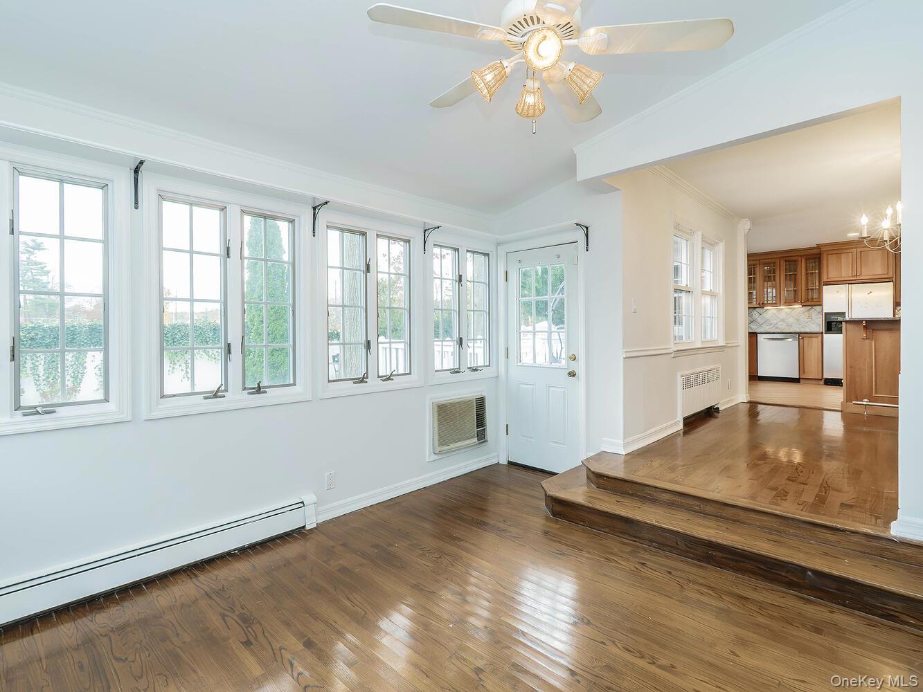 41 South 4th Street Locust Valley, NY 11560 - Photo 9 of 39 Unfurnished Den with dark wood finished floors, a baseboard heating unit, ornamental molding, radiator heating unit, and a ceiling fan