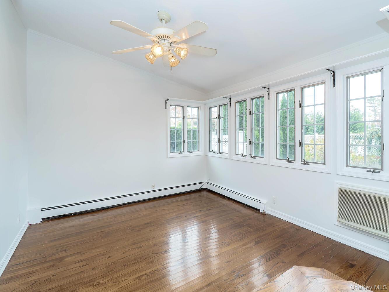 41 South 4th Street Locust Valley, NY 11560 - Photo 10 of 39 Empty room featuring hardwood / wood-style flooring, a baseboard heating unit, a ceiling fan, lofted ceiling, and an AC wall unit