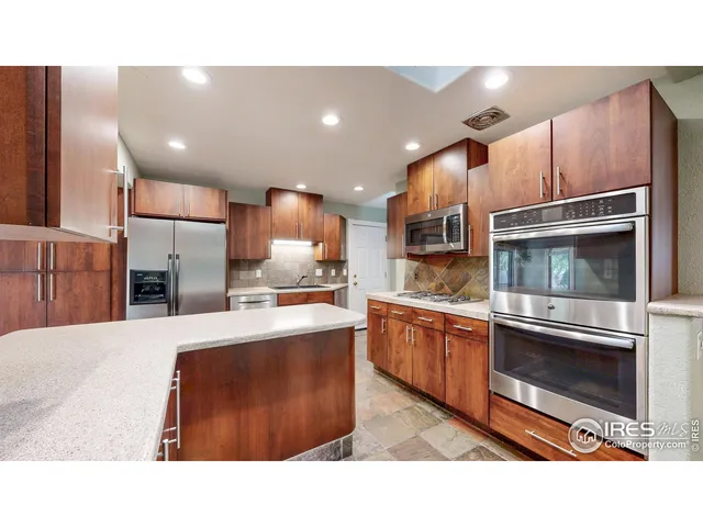 a kitchen with stainless steel appliances kitchen island granite countertop a stove top oven a sink and a refrigerator