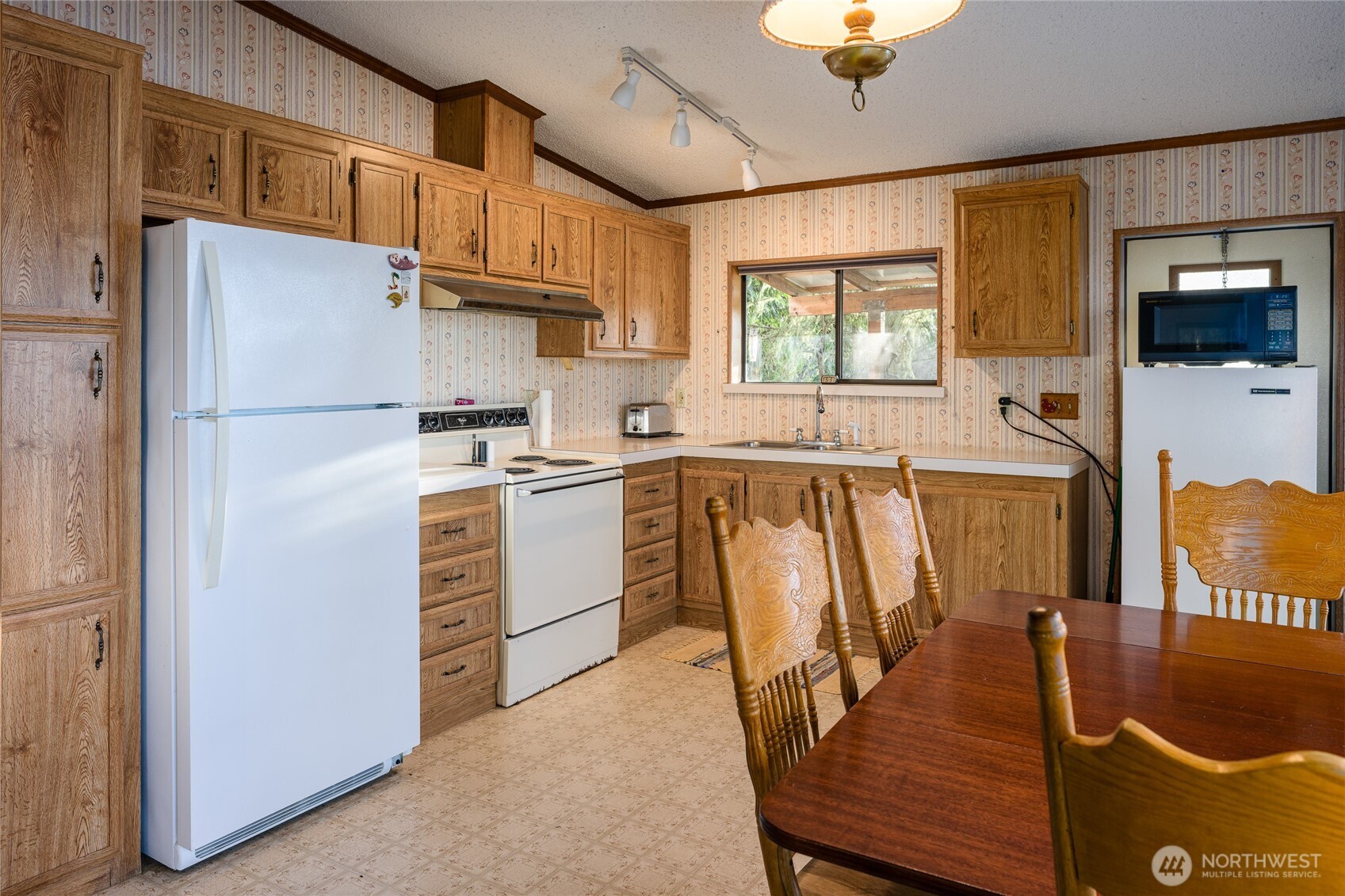 385 Doe Run Road Lopez Island, WA 98261 - Photo 17 of 31 a kitchen with stainless steel appliances granite countertop a refrigerator a stove a sink a dining table and chairs with wooden floor