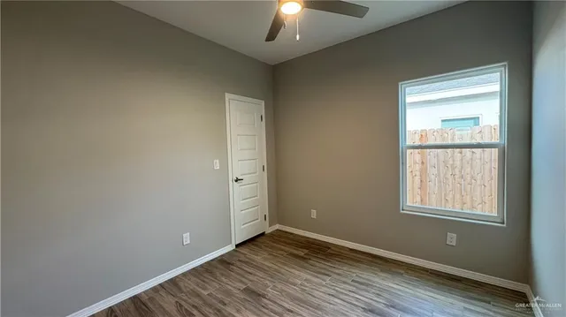 a view of an empty room with window and wooden floor