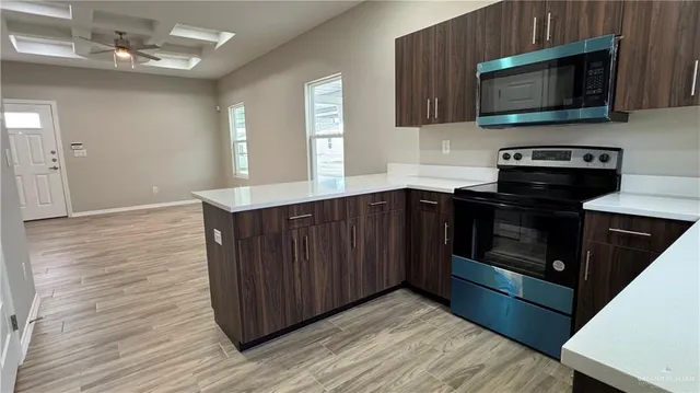 a kitchen with stainless steel appliances granite countertop a stove a microwave and wooden cabinets