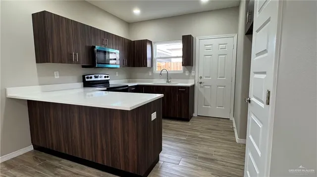 a kitchen with a sink a stove top oven and wooden floor