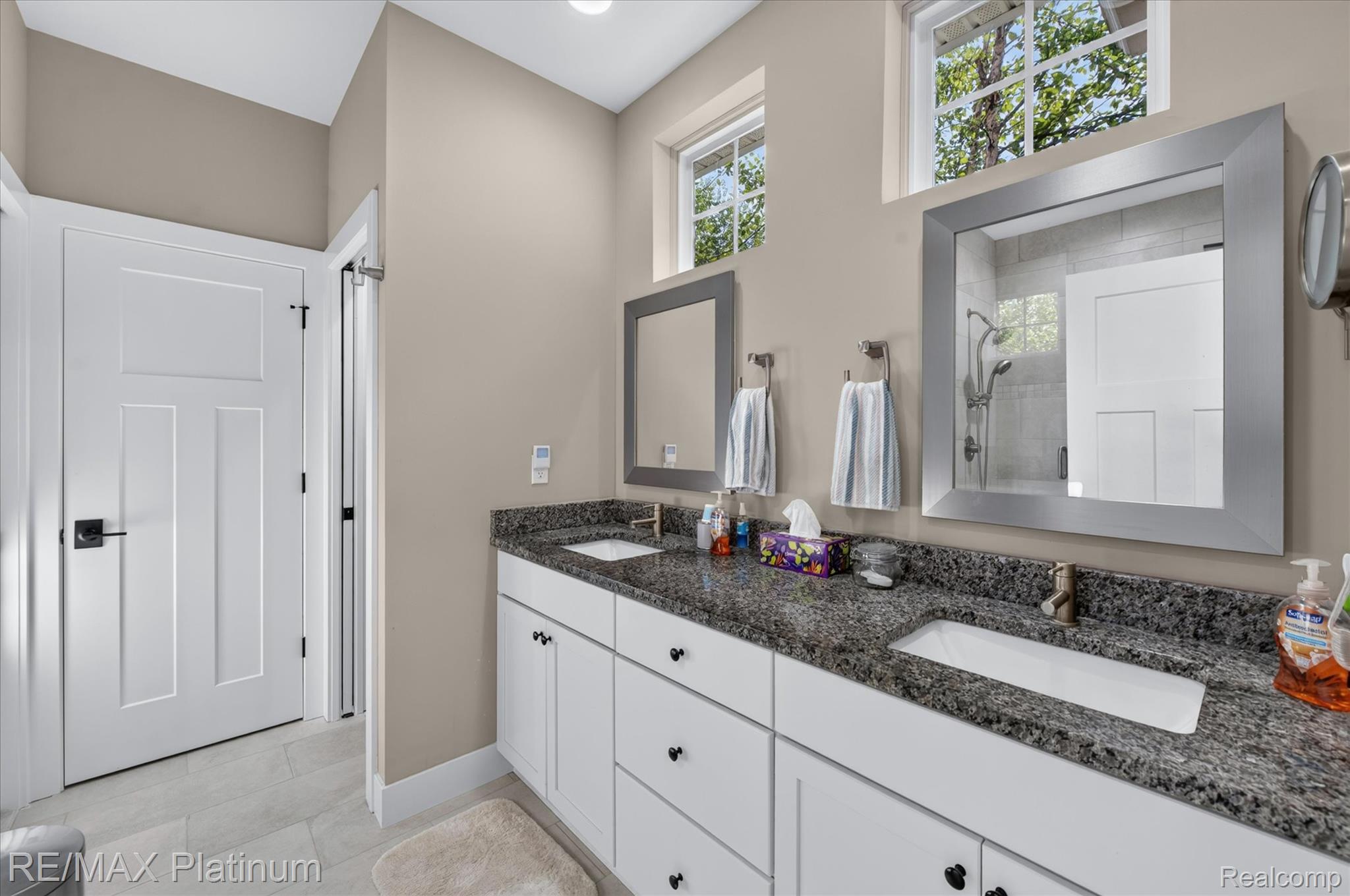 2676 Crooked Lake Road Howell, MI 48843 - Photo 26 of 60 Dual vanity with granite countertop and undermount sinks, white cabinetry with dark hardware, framed mirrors, and transom windows