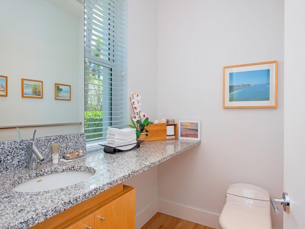 4253 Cutlass Lane Naples, FL 34102 - Photo 42 of 47 a bathroom with a granite countertop sink a mirror and a toilet