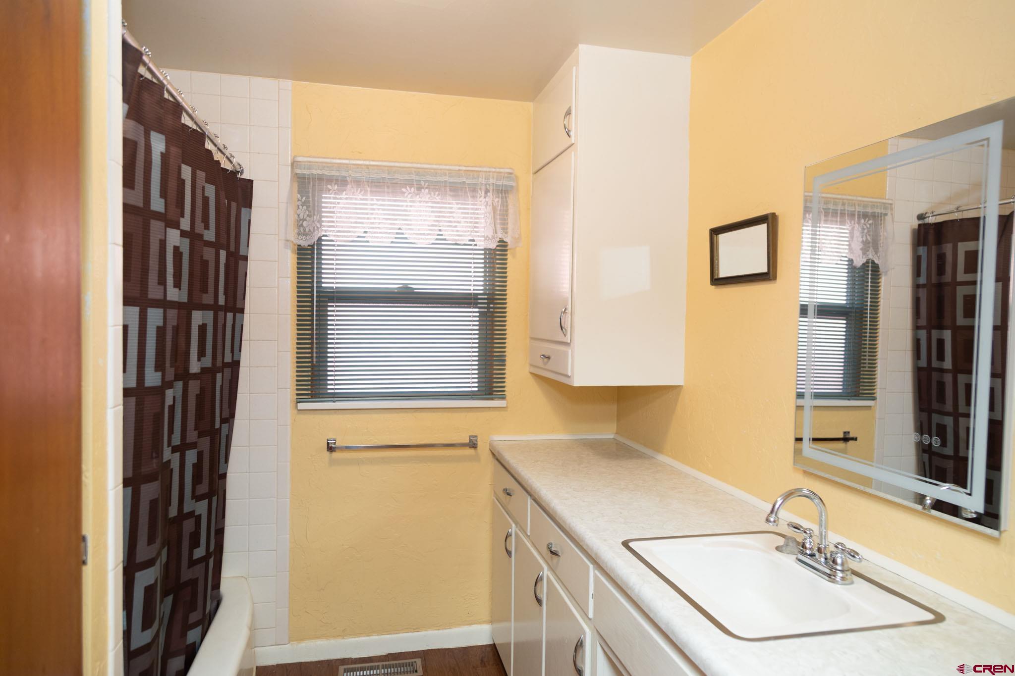 711 First Street Alamosa, CO 81101 - Photo 8 of 21 a bathroom with a sink a mirror and a shower