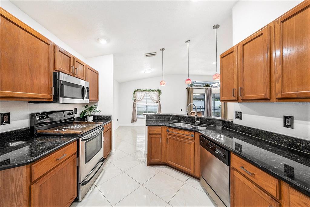 5644 Grindstone Loop Wesley Chapel, FL 33544 - Photo 14 of 29 a kitchen with stainless steel appliances granite countertop a stove a sink and a microwave
