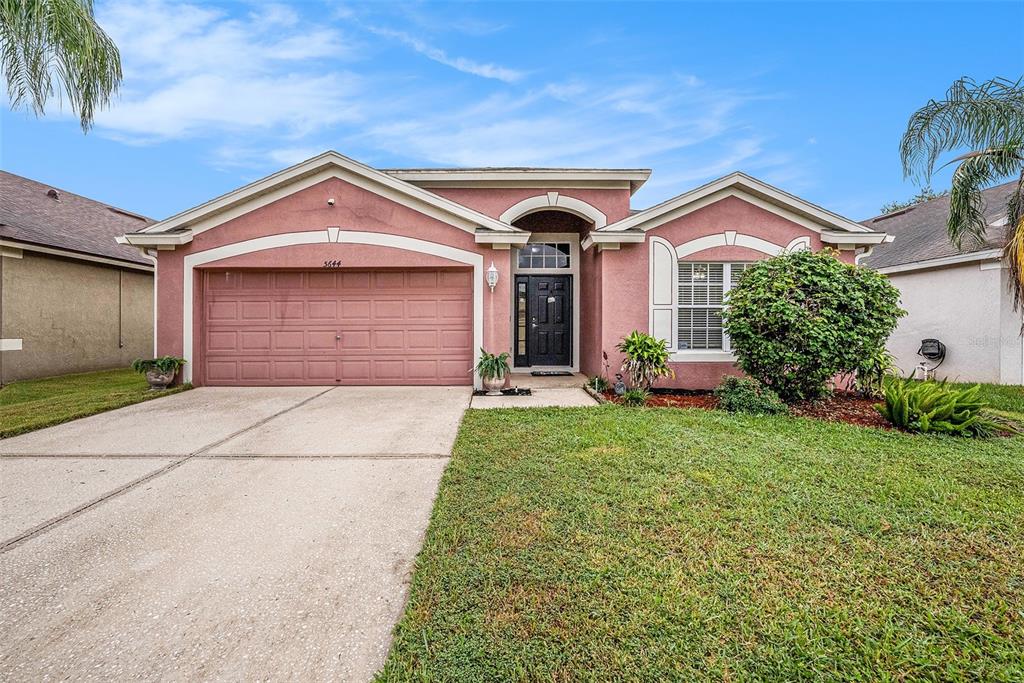 5644 Grindstone Loop Wesley Chapel, FL 33544 - Photo 3 of 29 a front view of a house with a yard and garage