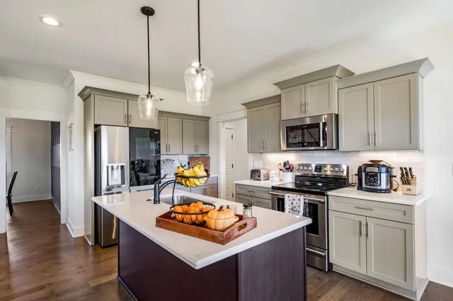 a view of a kitchen with kitchen island a sink a stove and chairs with wooden floor