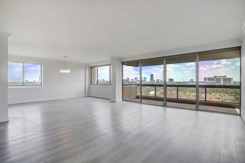 an empty room with wooden floor and windows with city view