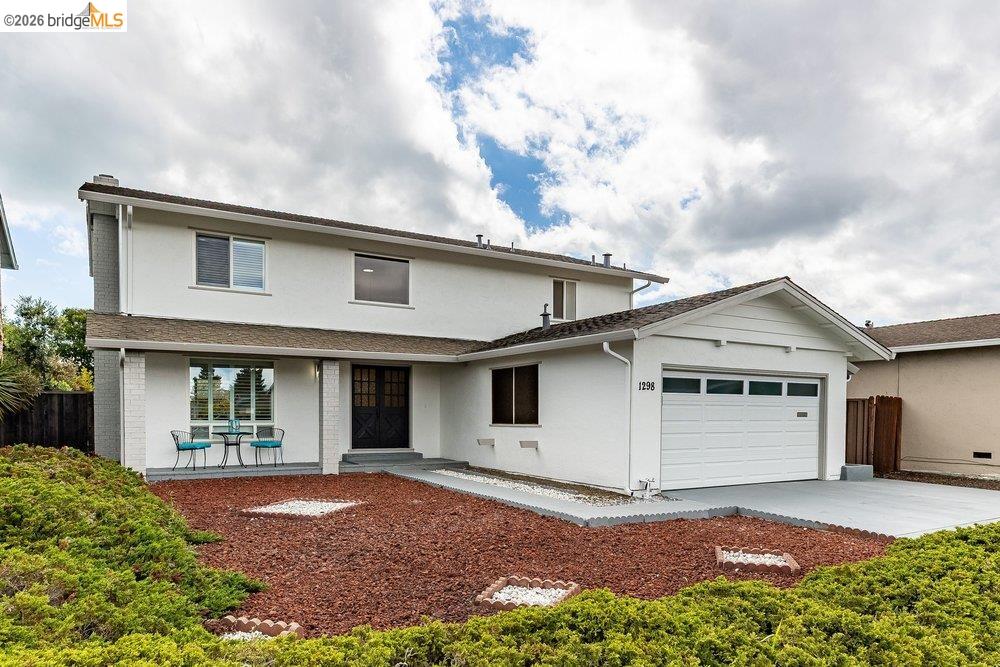 1298 Ribbon Street Foster City, CA 94404 - Photo 3 of 86 Two-story white stucco residence featuring a covered front porch, an attached garage, a driveway, and a landscaped front yard with ground cover and rock accents