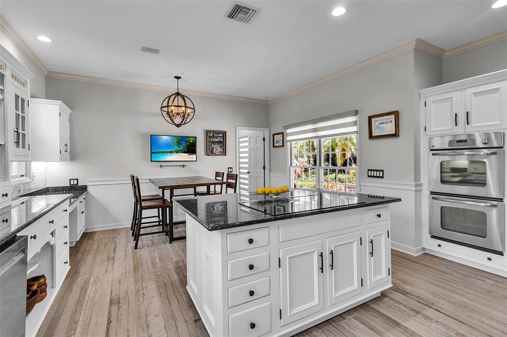 156 Bishopscourt Road Osprey, FL 34229 - Photo 34 of 84 a kitchen with stainless steel appliances granite countertop a stove a sink dishwasher and white cabinets with wooden floor