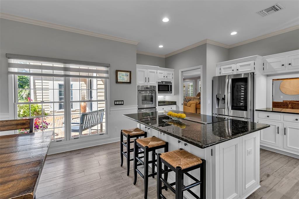 156 Bishopscourt Road Osprey, FL 34229 - Photo 38 of 84 a kitchen with stainless steel appliances granite countertop a stove top oven a sink dishwasher a dining table and chairs with wooden floor