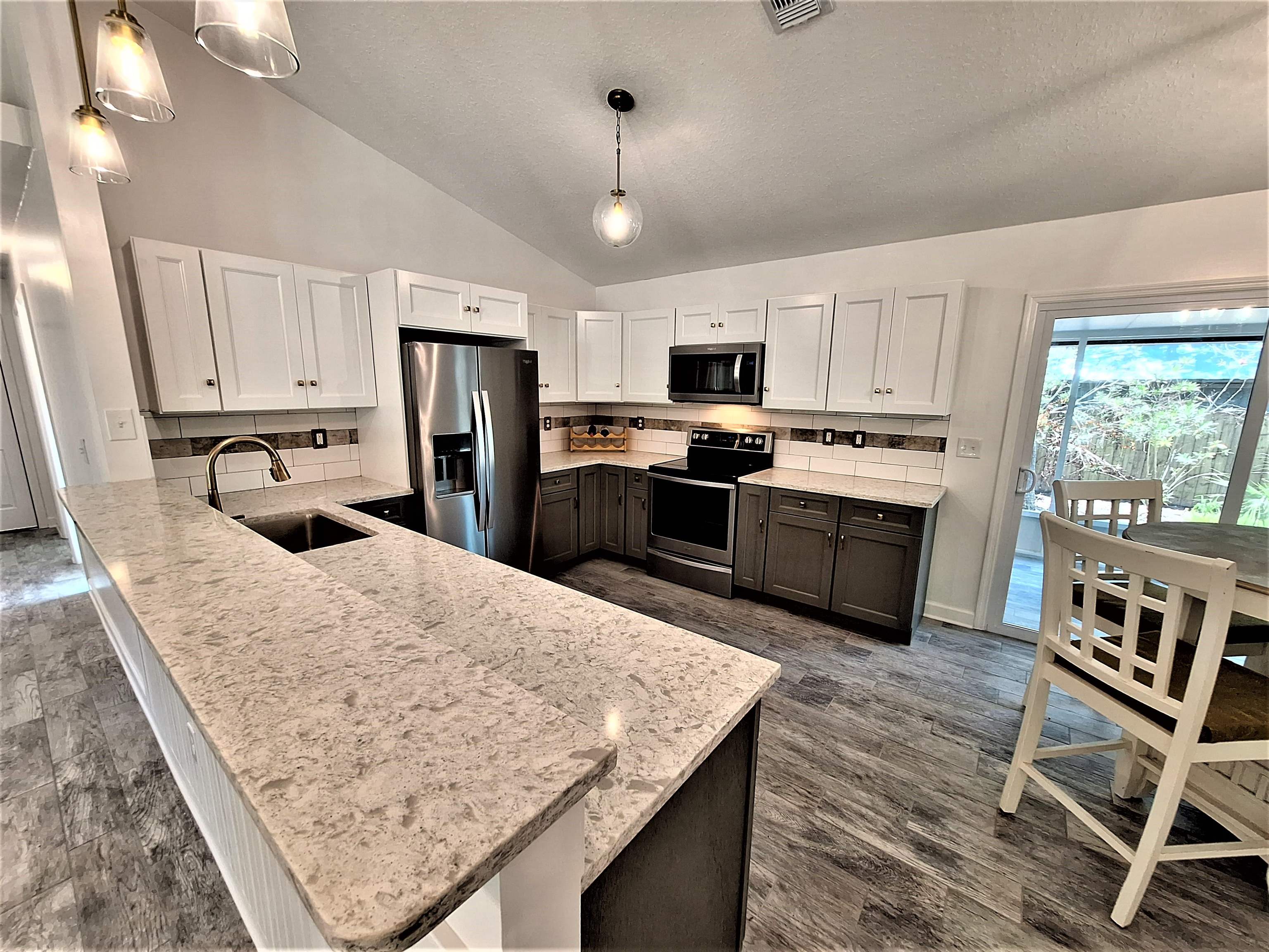 129 15th Street St. Augustine, FL 32080 - Photo 44 of 61 a kitchen with stainless steel appliances granite countertop a table chairs sink refrigerator and microwave