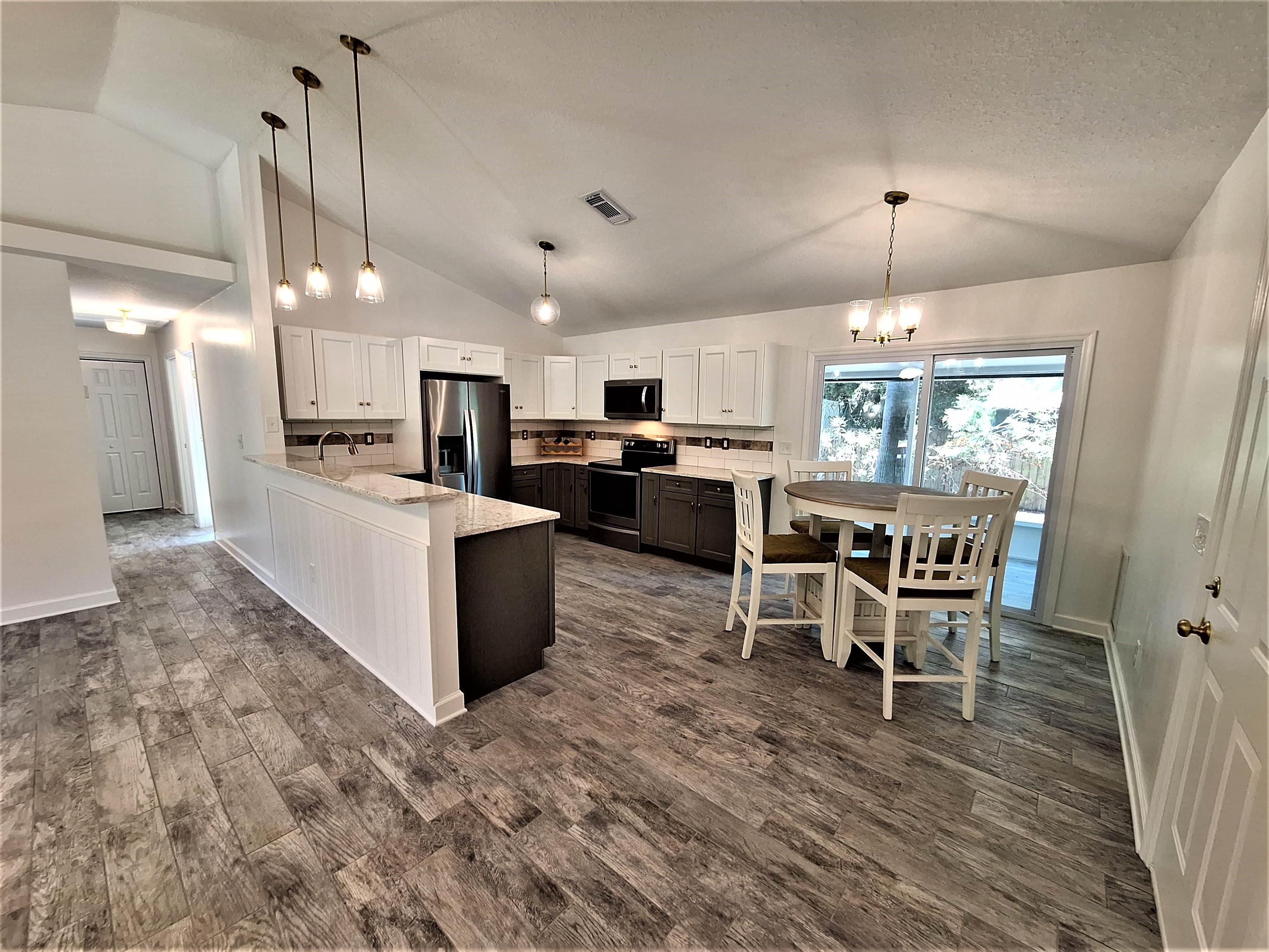 129 15th Street St. Augustine, FL 32080 - Photo 45 of 61 a kitchen with stainless steel appliances kitchen island granite countertop a dining table chairs and a refrigerator
