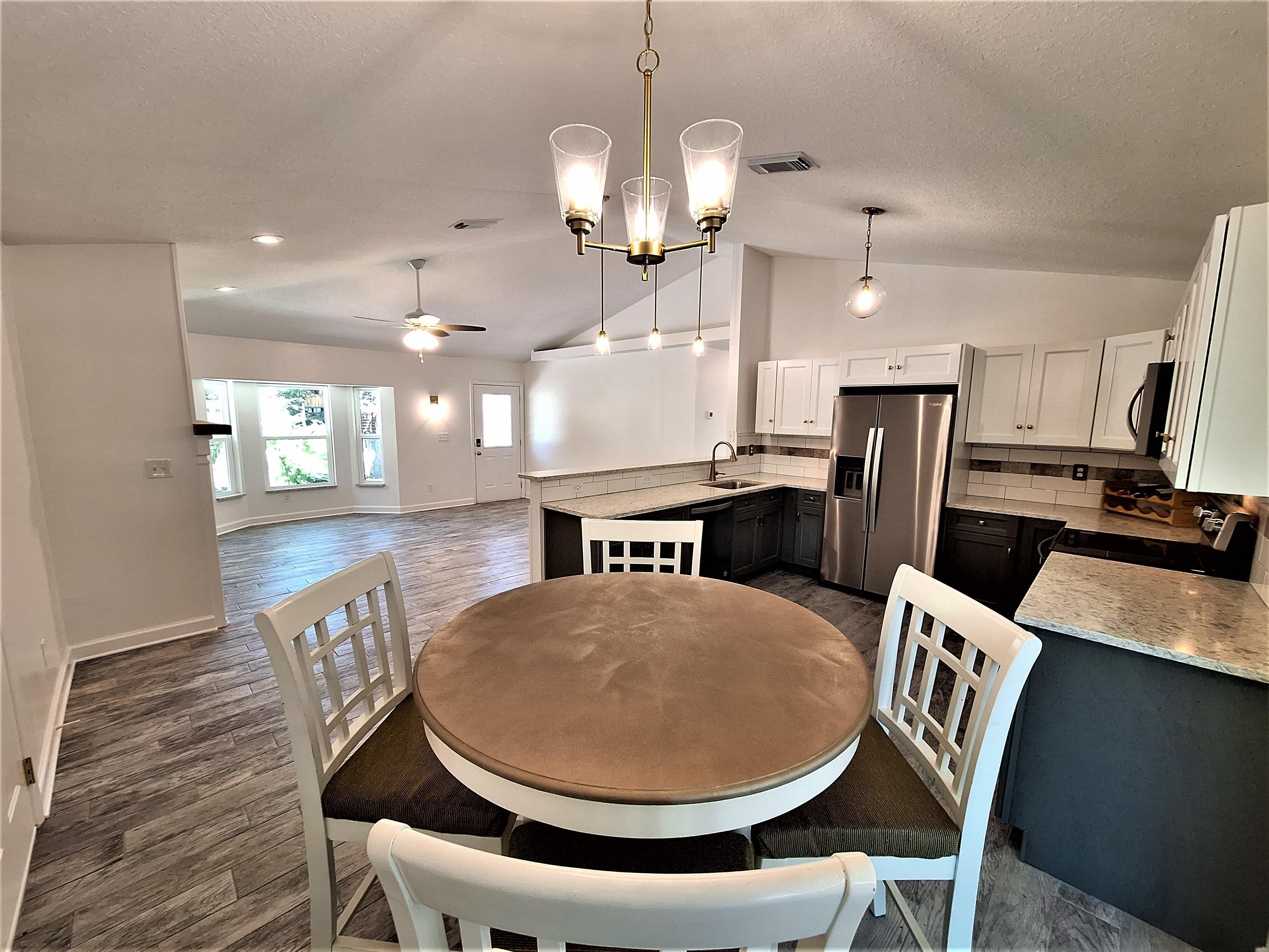129 15th Street St. Augustine, FL 32080 - Photo 7 of 61 a dining room with wooden floor a chandelier a glass table and chairs