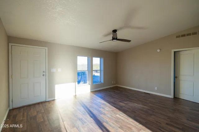 a view of an empty room with window and wooden floor